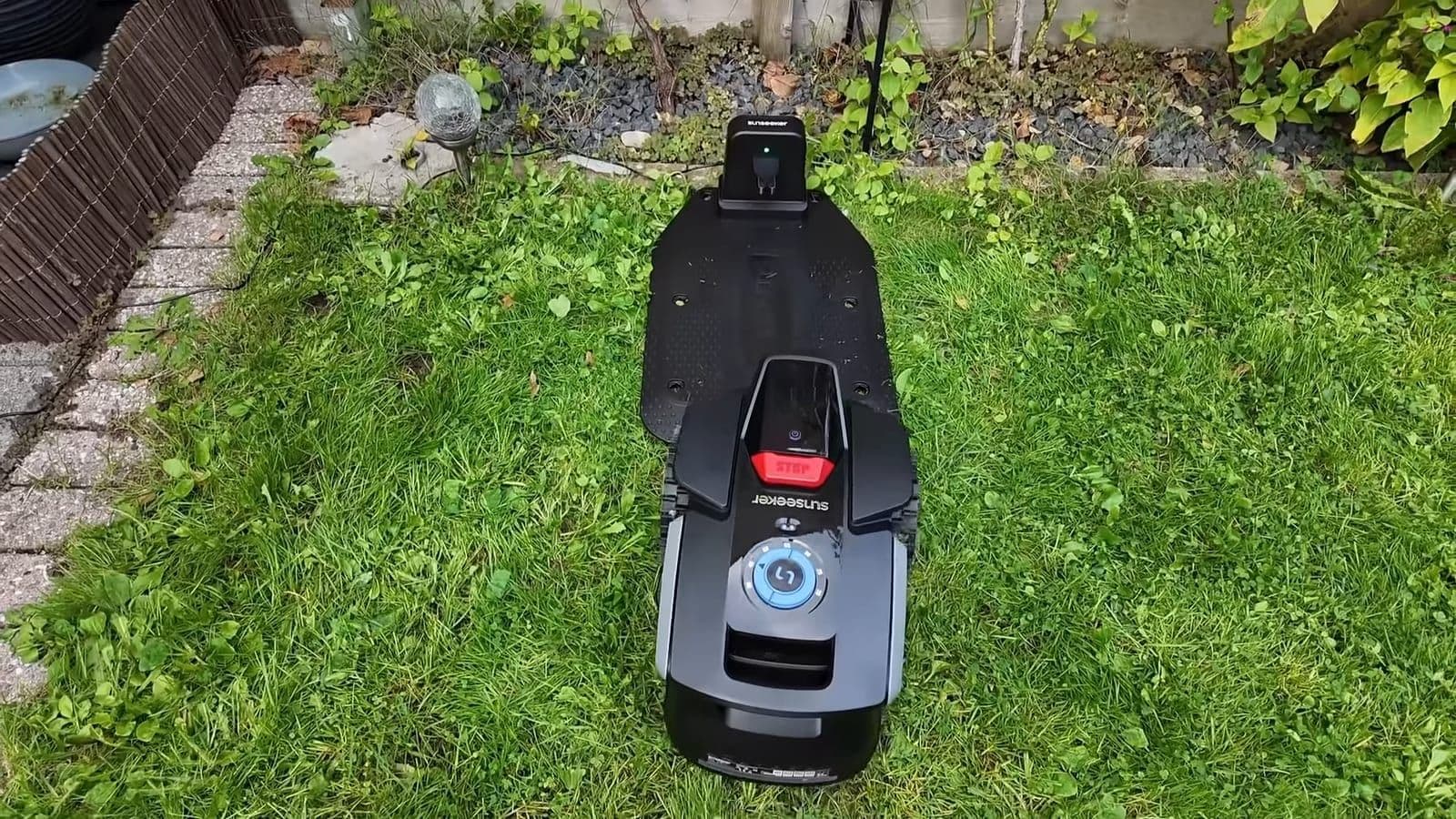 Sunseeker V1 robotmaaier van bovenaf gezien terwijl hij achterwaarts het laadstation op rijdt