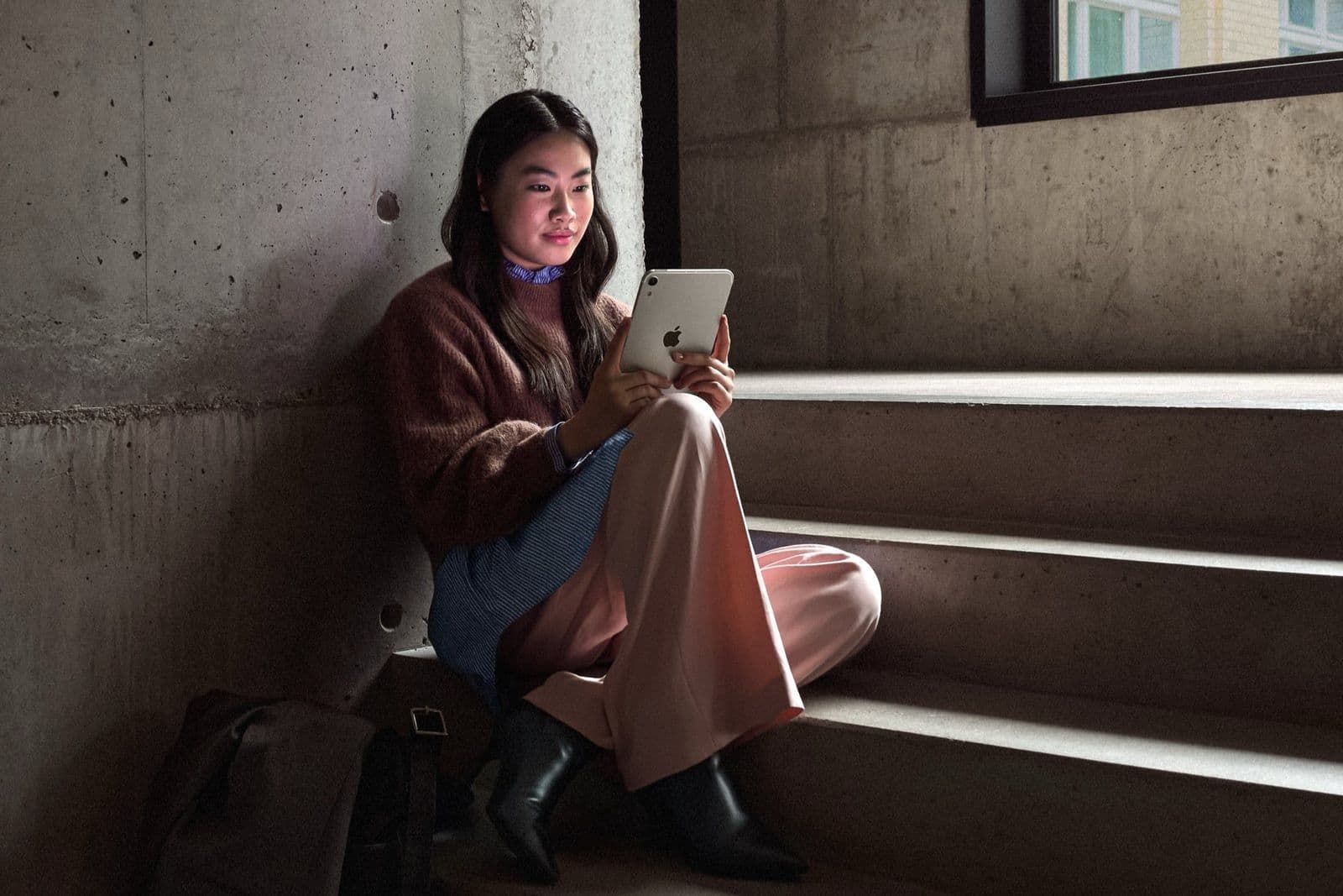 Vrouw zittend op een betonnen trap met de iPad mini in haar handen