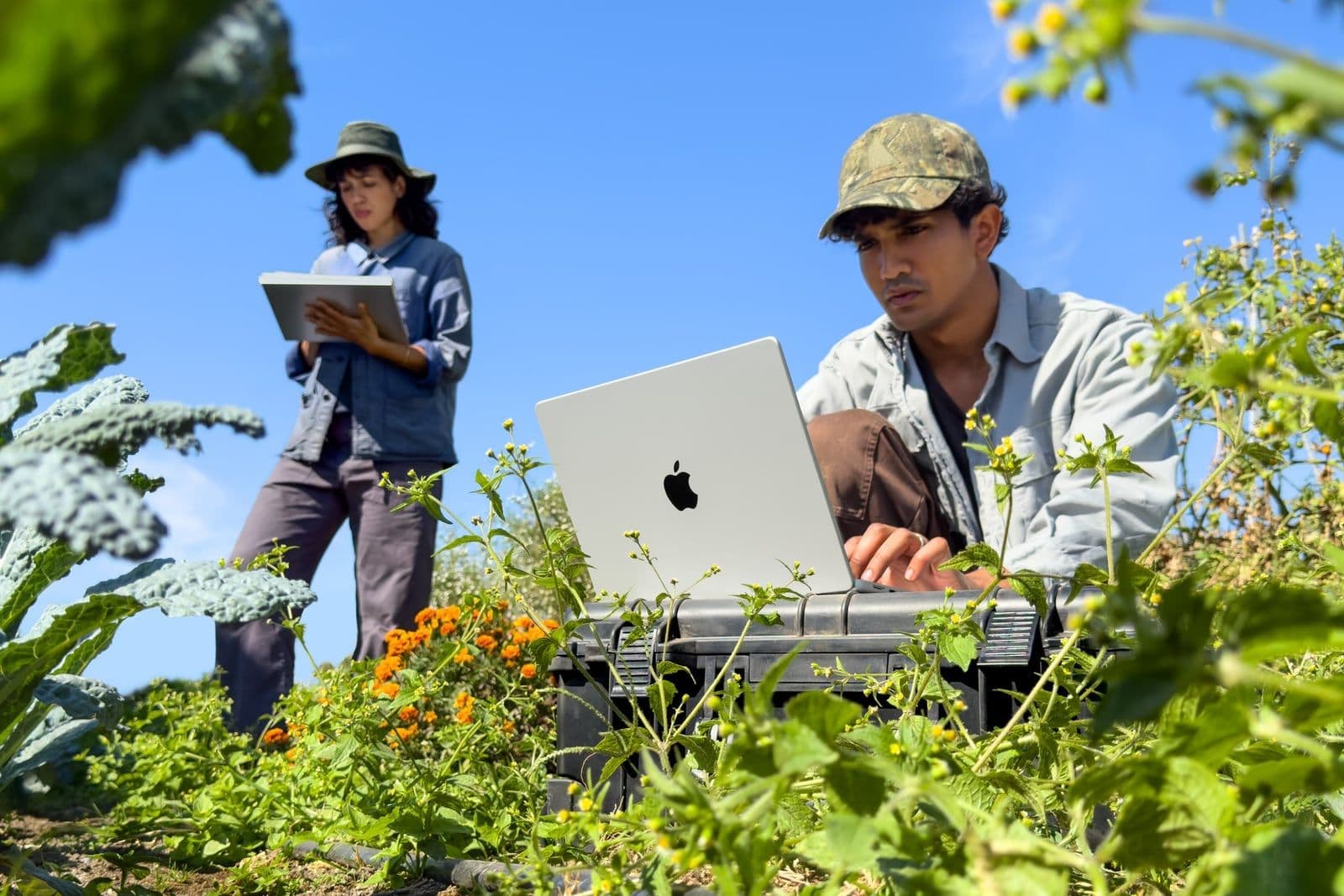 Twee onderzoekers werken buiten in een veld met een 14-inch MacBook Pro