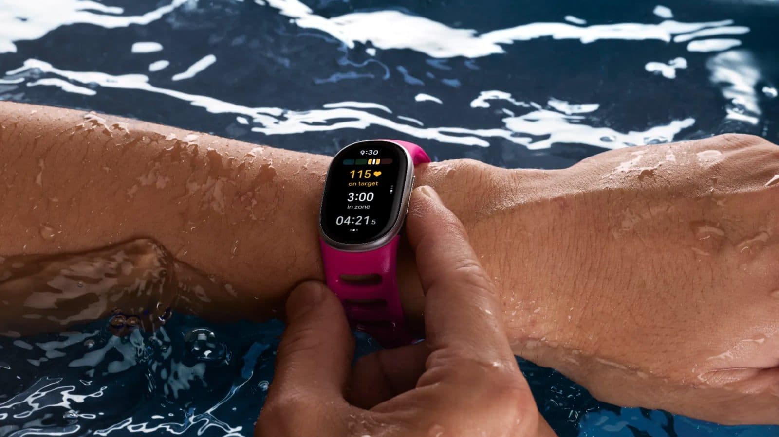 Hand met een Fitbit Edge onder water in een zwembad