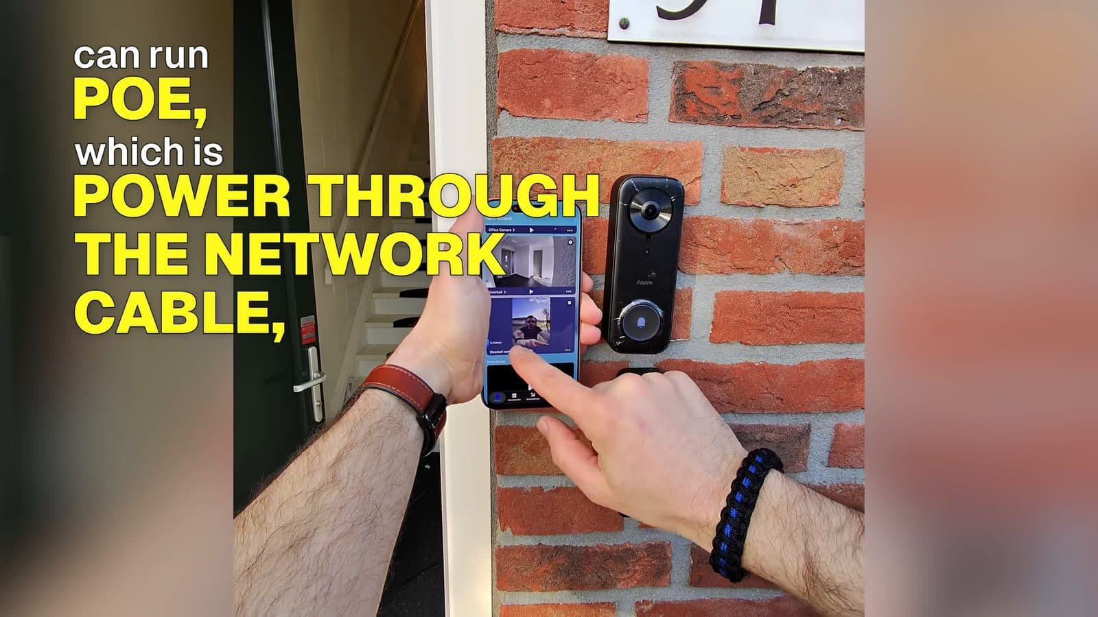 Holding a smartphone showing the Aqara Home app live view next to the mounted G400 doorbell