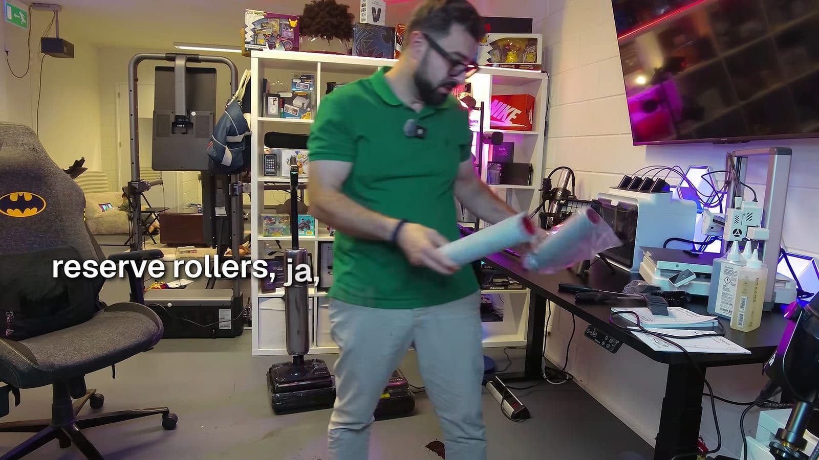 Zino in een groen shirt houdt twee reserverollers in plastic vast, met flessen reinigingsvloeistof op het bureau naast hem
