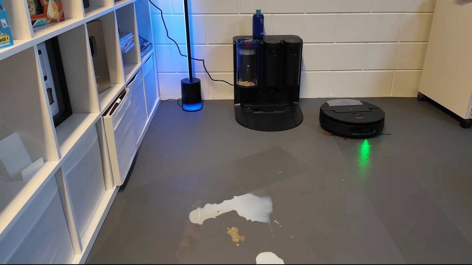 De robotstofzuiger rijdt richting een grote plas gemorste melk en koffie op de vloer