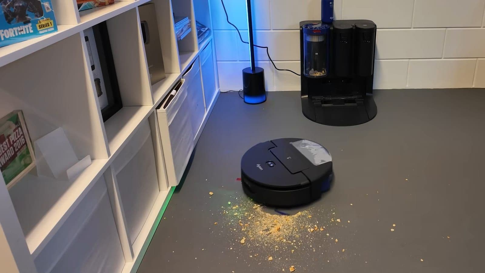 Robotstofzuiger rijdt over een grijze vloer vol verspreide crackerresten