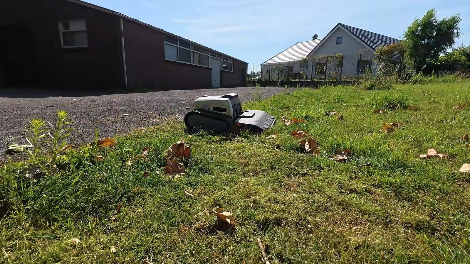 Lymow One Plus draait in hoog nat gras naast een stenen muur