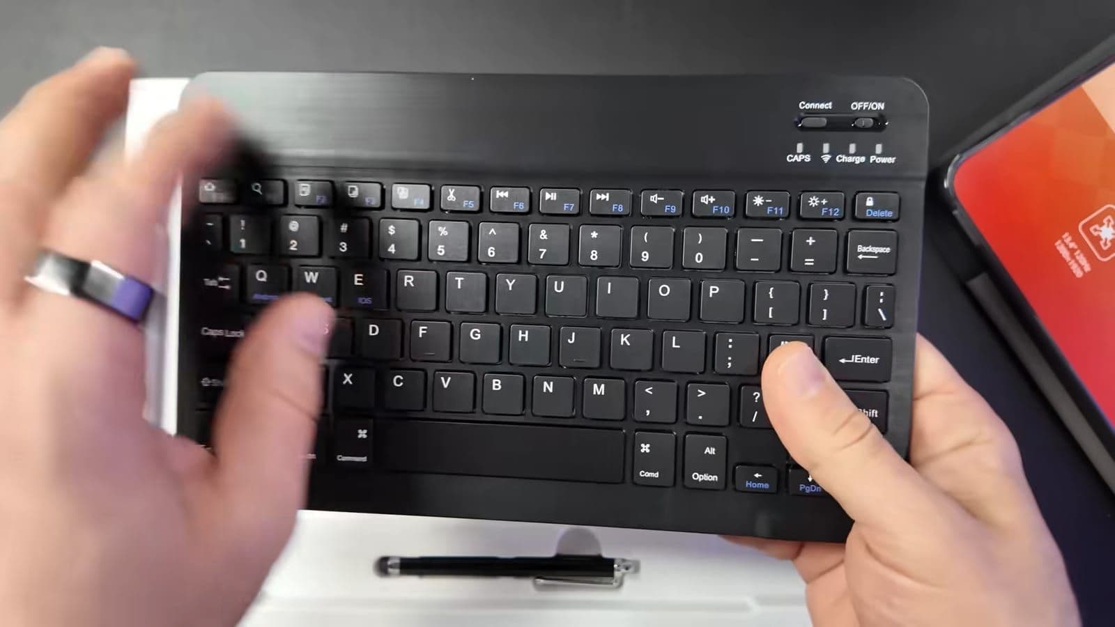 Handen die het meegeleverde zwarte bluetooth toetsenbord vasthouden