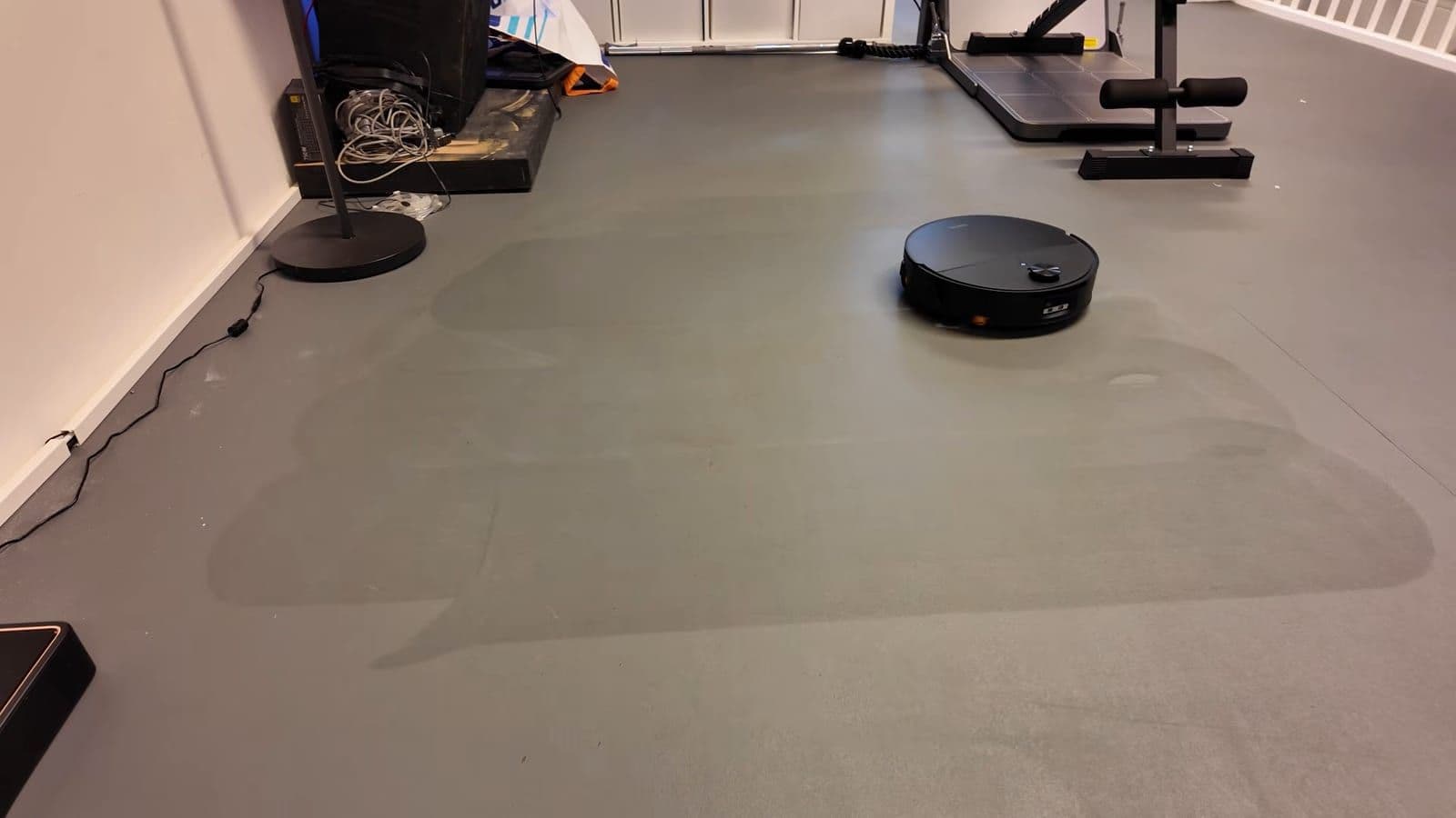 Grijze vloer met vochtige banen waar de robot net de koffie heeft opgedweild