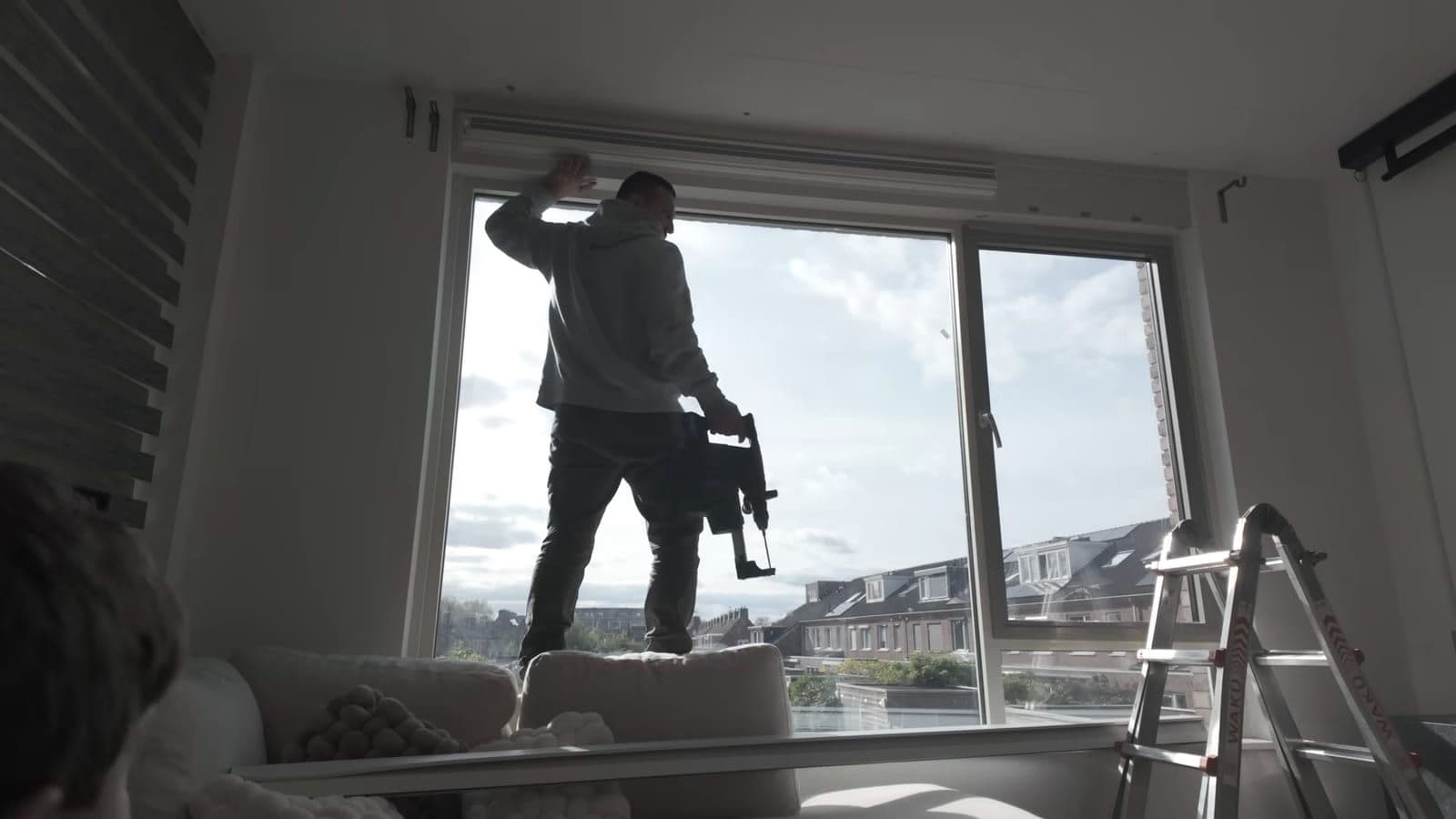 Two people mounting SmartWings blind brackets into a window frame using a ladder